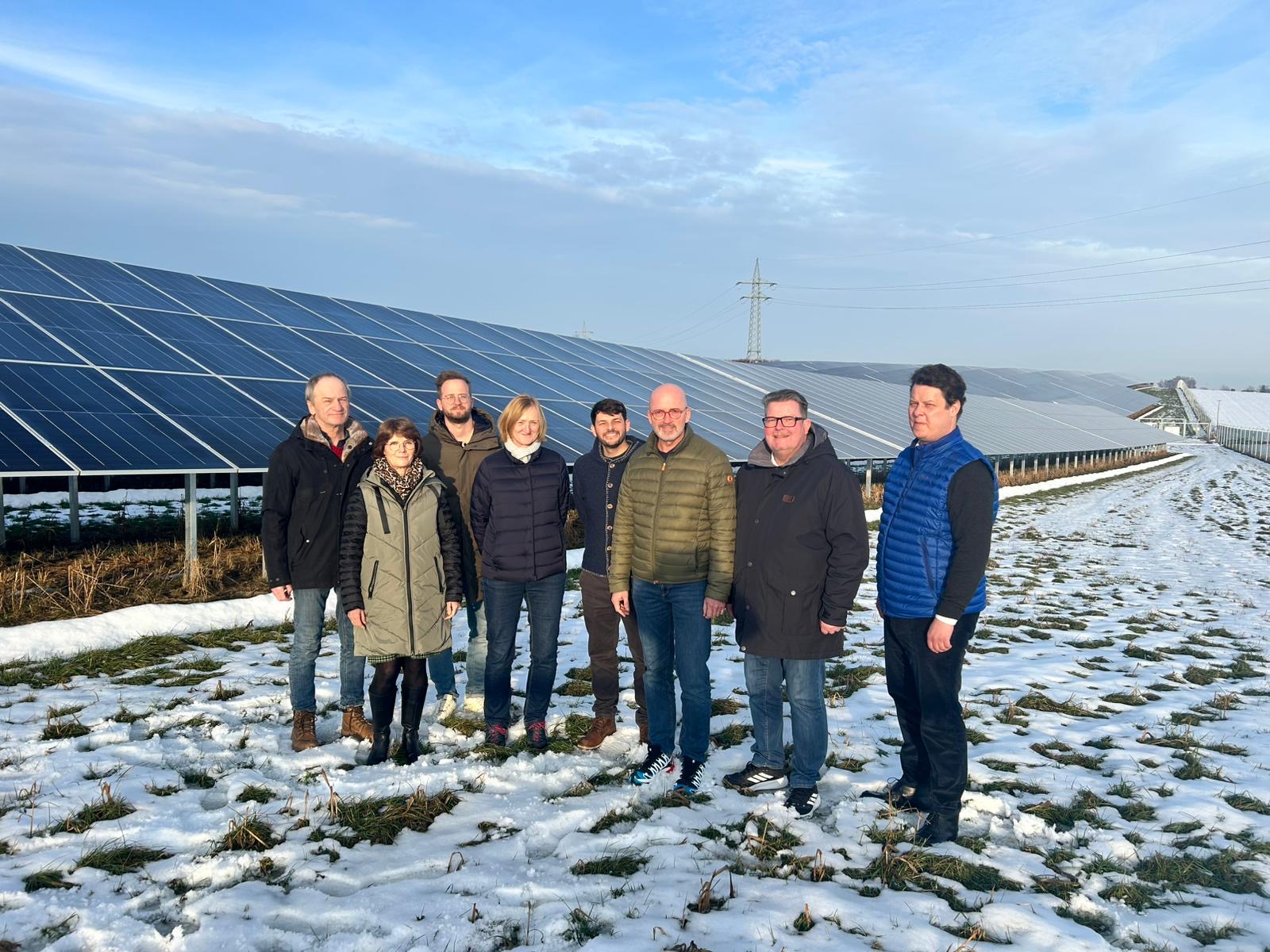 Sechs Männer und zwei Frauen stehen vor Reihen von Solarmodulen im Markt Ergolding.
